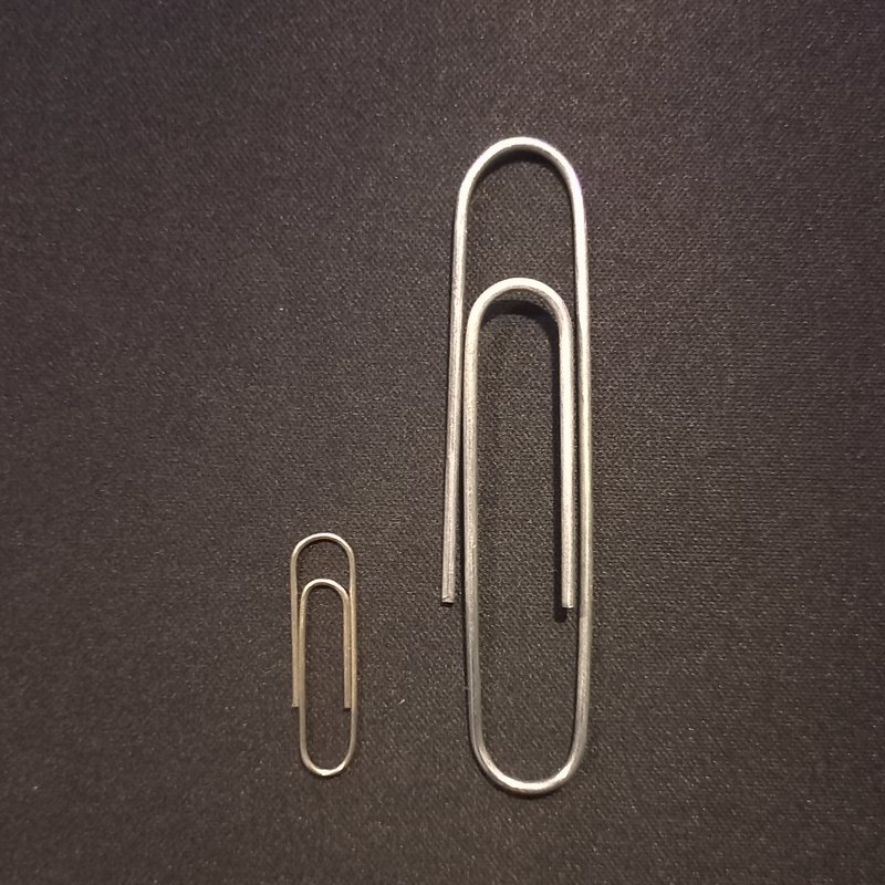 two silver paperclips. the one on the right is about three times bigger than the one on the left.