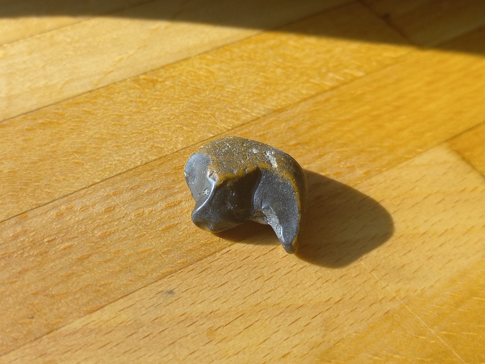 two colored rock with a smooth black part shaped like a sythe